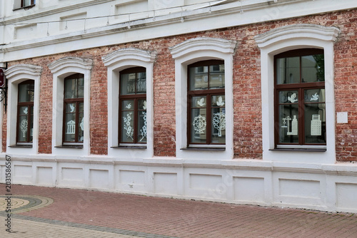 Quadro em tela Red brick building facade with two windows and white window sills in urban setti