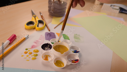 Obraz na płótnie Child Dipping Paintbrush into Yellow Paint Palette During Art Class