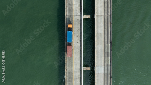 Aerial drone shot of container trucks driving to the port for cargo shipping.