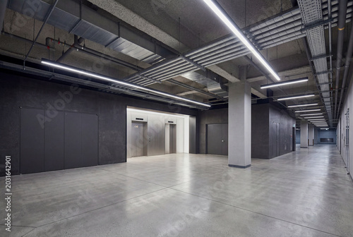 Empty modern parking structure interior with concrete columns and linear ceiling lights
