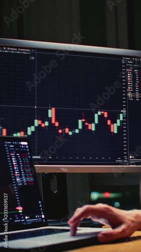 Man trader monitors market charts on laptop, screen and smartphone at home. Analyzing real-time trading data, considering investment strategies. Professional investor engaged in day trading, Evening