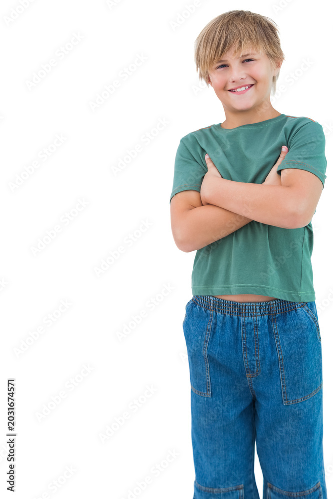 Fototapeta premium Child standing arms crossed smiling on white backdrop wearing green shirt, blue jeans, copy space
