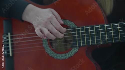 Close-up of female hand plucking guitar strings during performance.