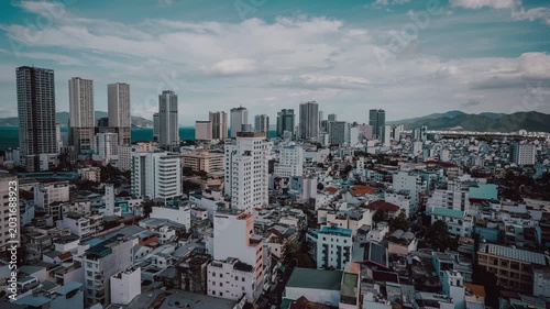 Nha Trang city skyline daytime timelapse, Vietnam. Scenic high-angle view of modern coastal resort cityscape with skyscrapers, buildings, moving clouds, and blue sea horizon.