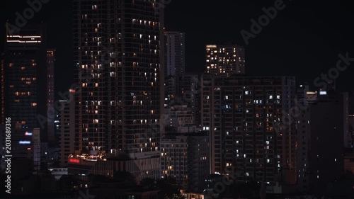 Close-up of illuminated skyscrapers and modern apartment buildings at night in Nha Trang, Vietnam. Glowing windows of high-rise hotels in popular Asian coastal resort city