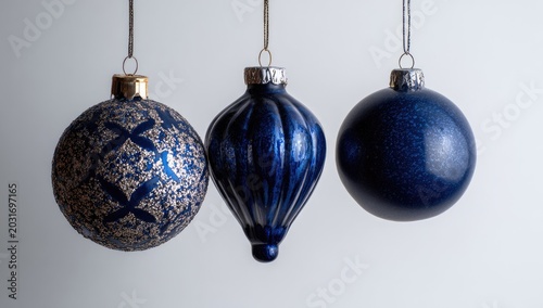 Three hanging christmas ornaments in blue against a white background