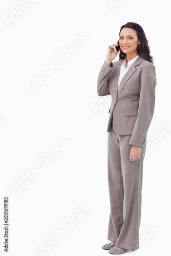 Fotografie Woman in 20s wearing light-gray pantsuit white blouse holding smartphone to ear,