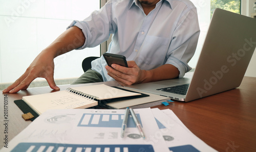 Businessman Using Smartphone With Laptop And Documents