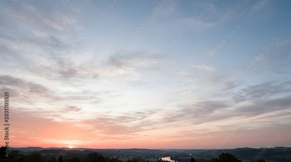 Obraz premium Beautiful panoramic sunset view over calm river winding through countryside hills and rural fields during dusk under colorful sky with scattered clouds.