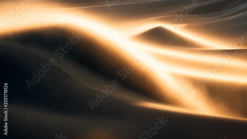 Golden desert sand dunes at sunset with dramatic light and shadows