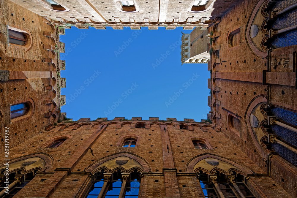 Fototapeta premium View to the sky in Palazzo Pubblico, an historic palace on the Piazza del Campo in Siena and one of the principal landmarks of the historic center.