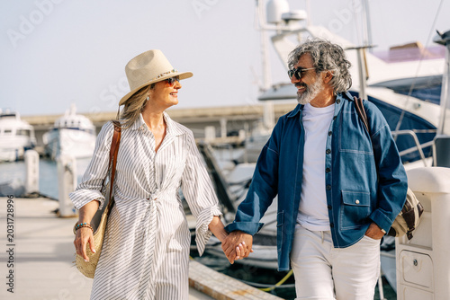 Happy senior couple enjoying summer vacation in luxury marina mature couple walking hand in hand enjoying luxury lifestyle
