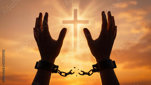 Silhouetted hands break free from chains, reaching towards a glowing Christian cross at sunset, symbolizing spiritual freedom and redemption