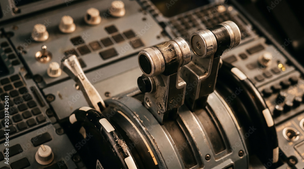 Naklejka premium Close-up view of the throttle levers and controls in the cockpit of an aircraft, showcasing the intricate technology and precision engineering involved in flight operations and aviation