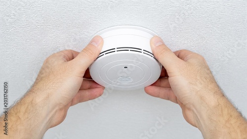Man Installing Smoke Detector Fire Alarm on Ceiling for Home Safety