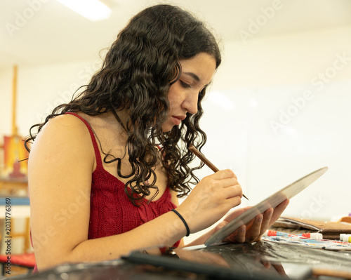 Canvas Print Young woman artist concentrating on painting in studio