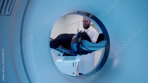 Patient seen inside circular MRI scanner tunnel during medical scan, showing high-tech radiology diagnostics and clinical examination process.