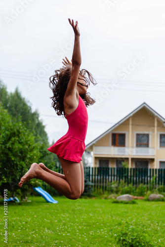 Free child leaps through green backyard lawn with unrestricted physical expression and joyful movement outdoors. Carefree little girl experiences true freedom of body and spirit on day in garden. Kid.
