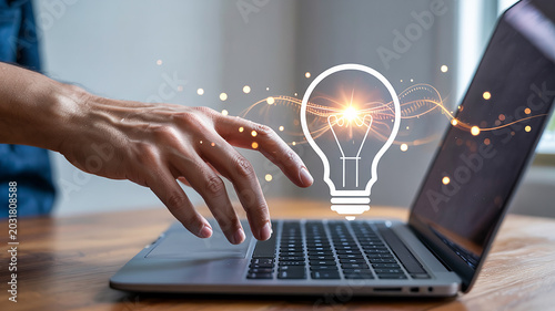 Hand Typing on Laptop with Glowing Lightbulb Idea Symbol