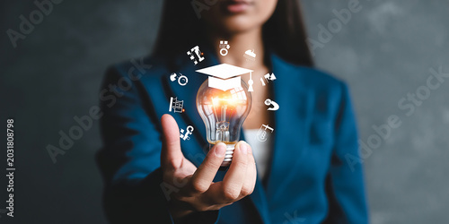 Person holding a glowing lightbulb with education icons