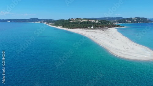 Aerial view of the white sand spit of Possidi Beach surrounded by turquoise waters and green hills in Greece.