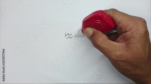 Hand Using Correction Fluid to Erase Writing on Paper