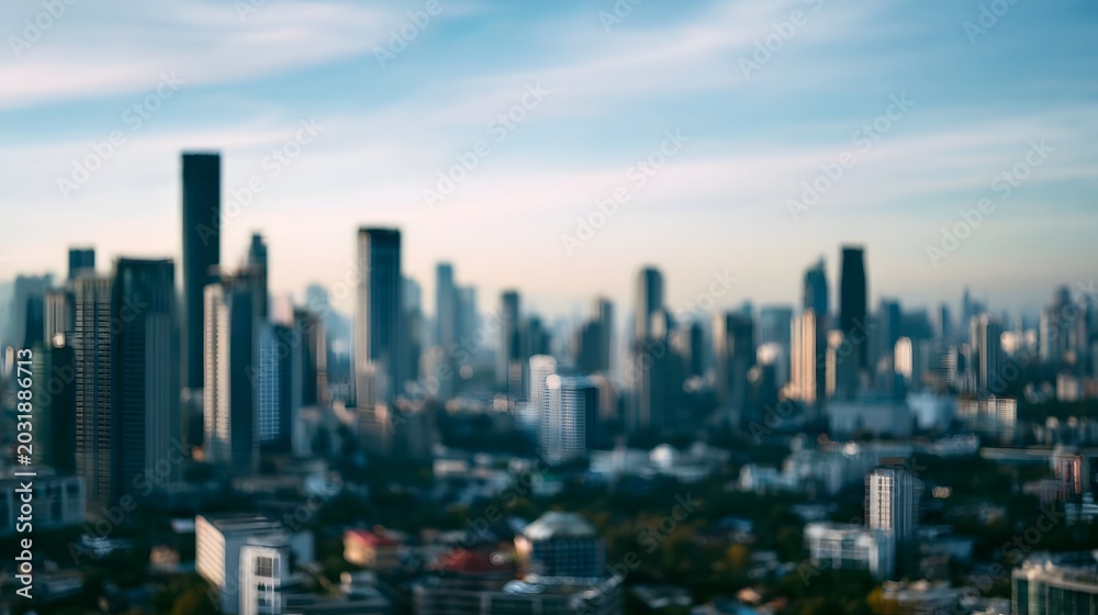 Fototapeta premium Blurred cityscape background featuring tall modern buildings under a bright blue daylight sky