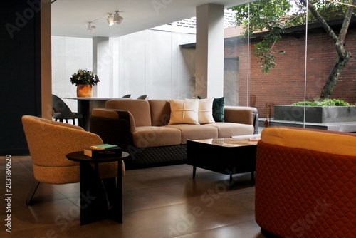 Foto A high-end contemporary lounge or living room setup featuring a stylish brown fabric sofa, minimalist armchairs, and a low-profile coffee table