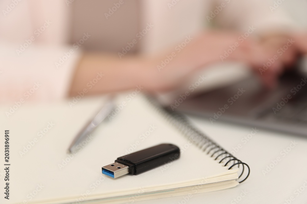 Fototapeta premium Woman with USB flash drive working on laptop at desk, selective focus