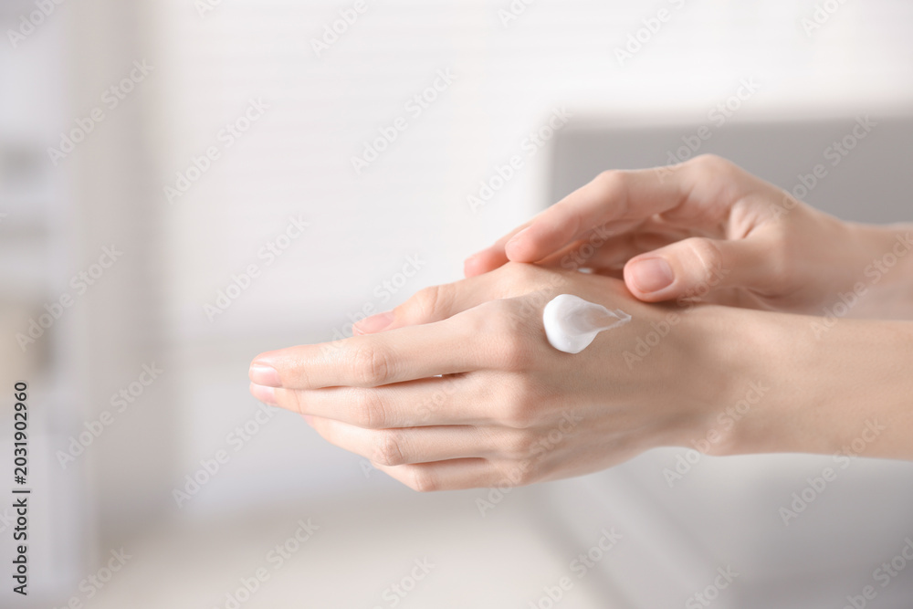 Naklejka premium Woman applying hand cream at home, closeup. Space for text