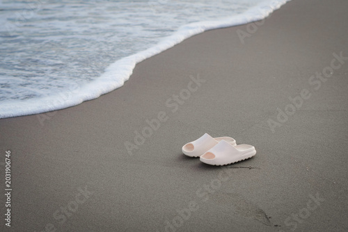 Fotografía a pair of sandals on the beach, the owner is enjoying the summer