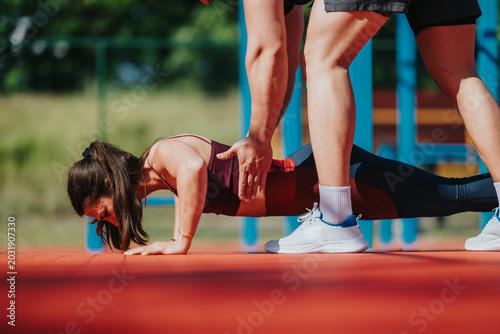 Cuadro en lienzo A female athlete performs a push-up while a personal trainer assists and supervises her form