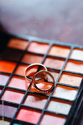 фотографія Golden rings placed on a vibrant makeup palette symbolize a union of beauty, romance, and artistic expression