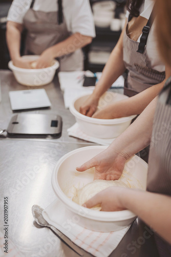Bakers knead sourdough dough in a busy kitchen while preparing for a pizza-making class in the afternoon at a local bakery