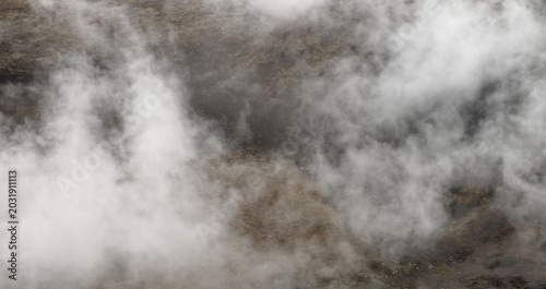 Fotografía Thick white fog drifts across a vast mountain range, creating a dramatic, ethereal atmosphere