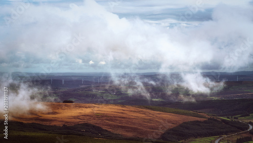 Thick white clouds hang low over a vast, undulating landscape.