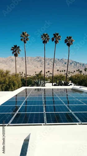 Minimalist Palm Springs Modern House With Solar Panels On Roof And Palm Trees Against Mountain