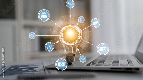 Fotografie This image represents innovation and creativity with a light bulb surrounded by technology icons, symbolizing digital connections and modern communication in the workspace