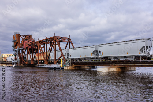 A train of grain hopper cars crossing a railroad bridge.