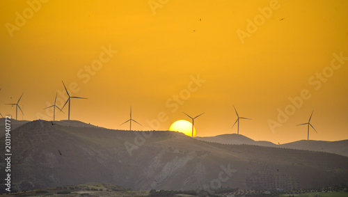 Wind turbines in mountainous region landscape in Taza, Morocco during dusk with setting sun, renewable energy for clean environment