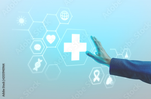 Photography Hand reaching toward glowing medical cross with healthcare icons