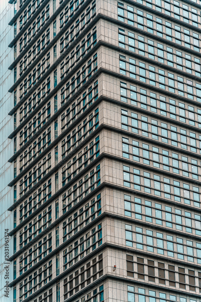 Fototapeta premium Modern highrise office building corner with repeating blue glass windows pattern