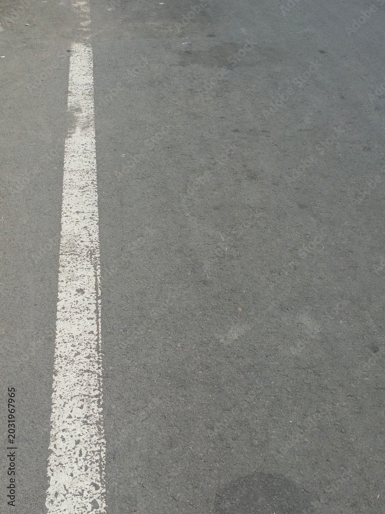 Fototapeta premium White solid road marking line on a gray asphalt street surface. 
