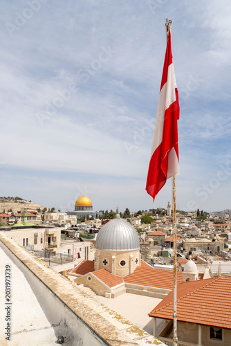 Waving Austrian flag in front of Jerusalem Old City as seen from Austrian Hospice. View at Church of Our Lady of Sorrows, Dome of the Rock on the Temple Mount and Al-Aqsa Mosque