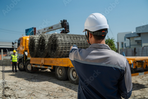 Fotografi Construction site manager pointing and directing worker for unloading steel wire mesh delivery from truck