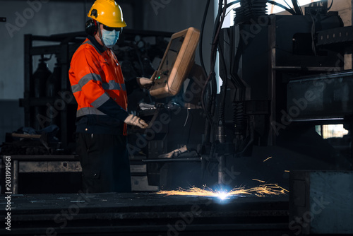 Smart industrial manufacturing automation technology concept. Professional operator worker controlling cnc plasma cutting machine for heavy steel metal fabrication process in commercial factory.