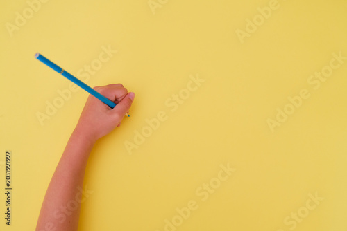 Left-handed child's handwriting with a blue pencil on a yellow background. Left-handed person's day