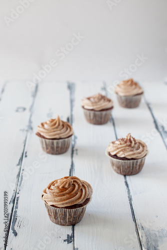 Fényképezés mocca cupcake with cream on a white wooden table