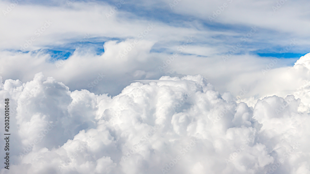 Fototapeta premium Fluffy clouds cover the sky during a sunny day in the afternoon with blue peeking through