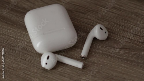 A charging case for wireless headphones lies on the table.
Close-up of white wireless headphones